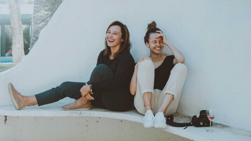 Two friends having a good time while sitting outdoors. From the article: "Can you have different attachment styles with different people?"