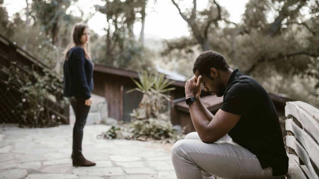 A couple at a park, showing distress. From the article: "How to respond when an avoidant pulls away"