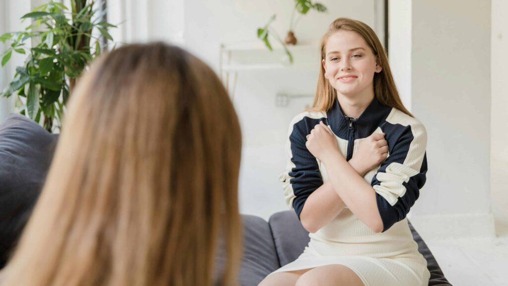 A girl signing love in a therapy setting. From the article: "How to stop being a people pleaser"
