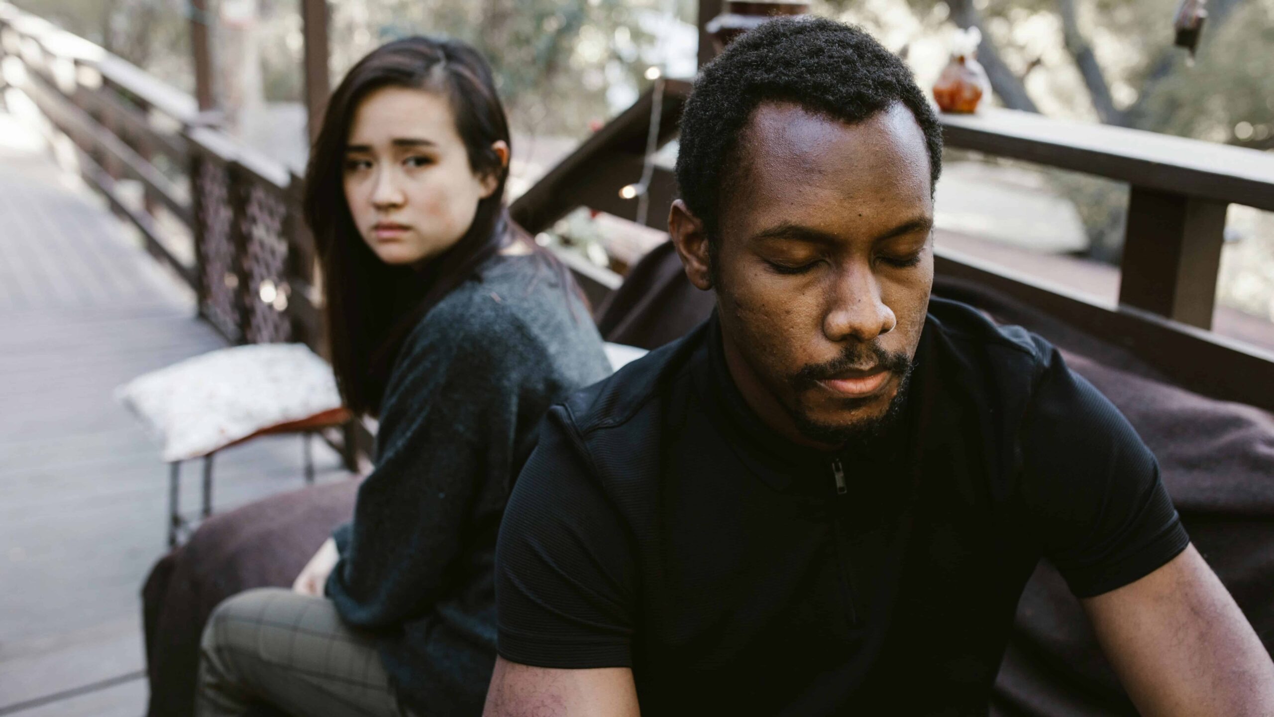 A couple distant with each other sitting on a beach. From the article "How to heal avoidant attachment style"